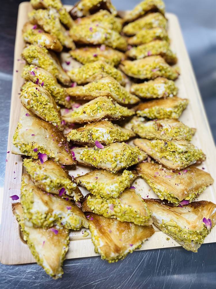 Baklavas à la pistache et aux pétales de rose sur une planche en bois