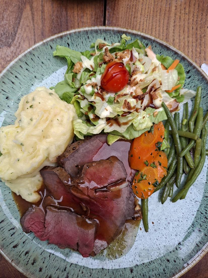 Rôti de bœuf, écrasé de pommes de terre, haricots verts et carottes dans une assiette bleutée