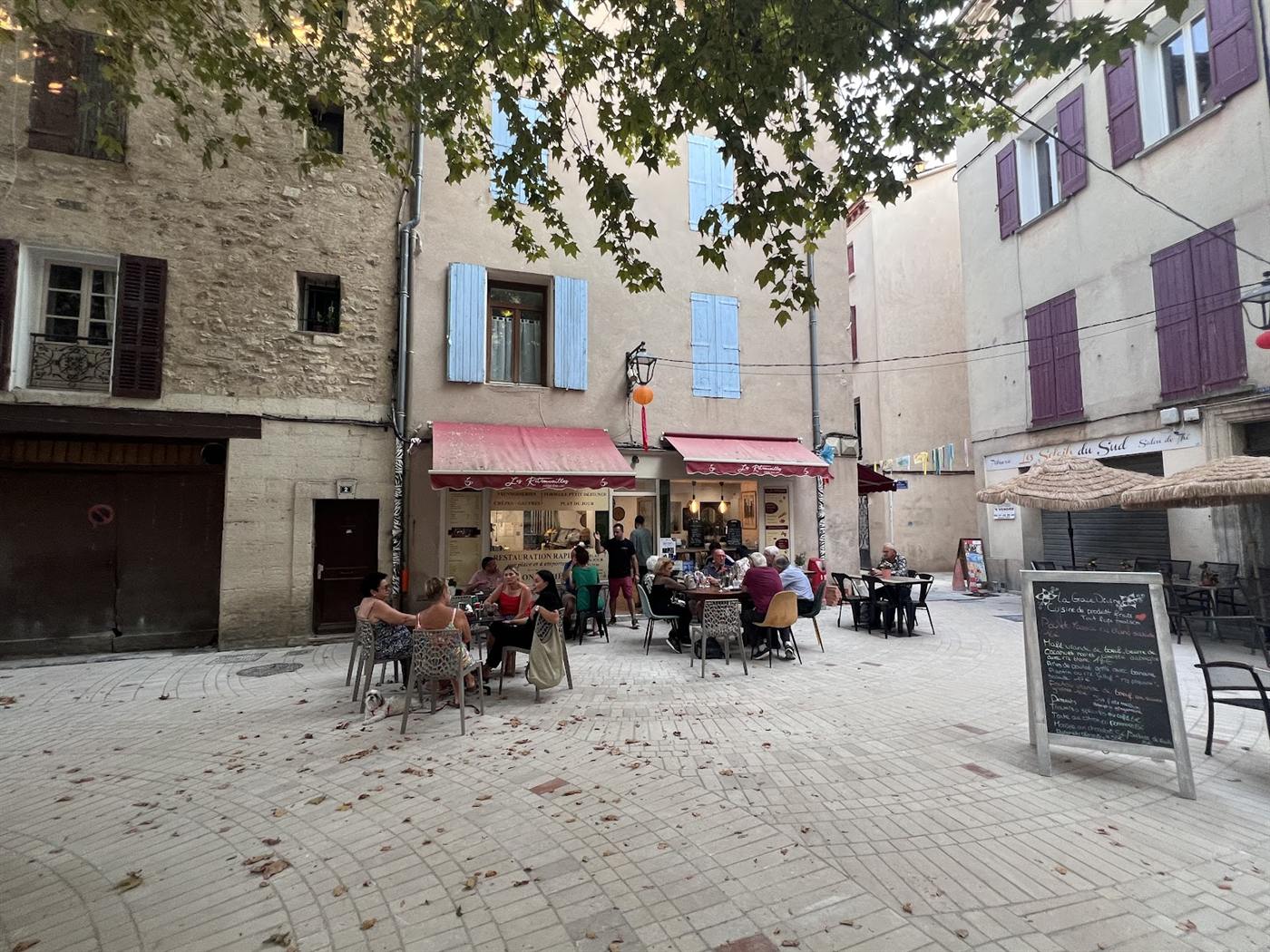 La terrasse des Retrouvailles sur la petite place du centre ancien, pleine de convives