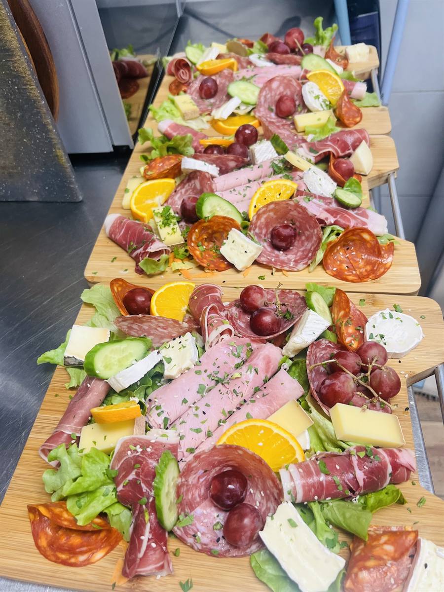 Longues planches de charcuterie, fromages, crudités, oranges et raisins